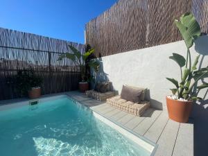 a swimming pool next to a wooden fence with plants at Aldara Sitges in Sitges