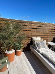 a bench on a deck with potted plants at Aldara Sitges in Sitges