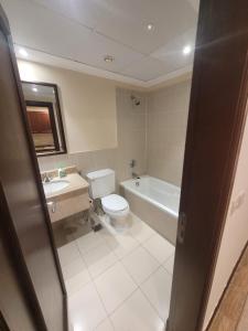 La salle de bains est pourvue de toilettes, d'une baignoire et d'un lavabo. dans l'établissement Lotus Apartments, à King Abdullah Economic City
