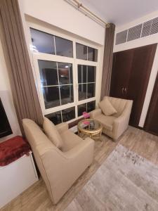 a living room with two chairs and a large window at Lotus Apartments in King Abdullah Economic City
