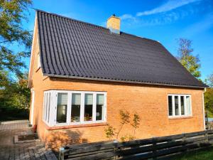 uma casa de tijolos com um telhado preto em Nygaard Guesthouse em Hjørring