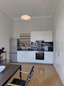 Apartment Theatrum في زغرب: مطبخ كبير مع خزائن بيضاء وطاولة sidx