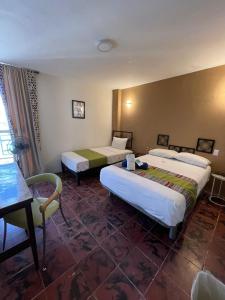 Habitación de hotel con 2 camas y mesa en Hotel Flamingos en Guadalajara