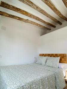 una camera bianca con letto e soffitti in legno di minicasita tipica a Zuheros