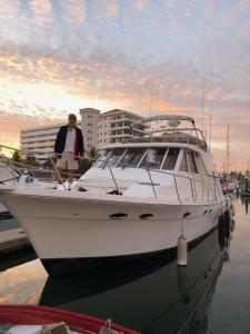 un hombre de pie en un barco en el agua en Marina Yacht Living Experience en Puerto Vallarta