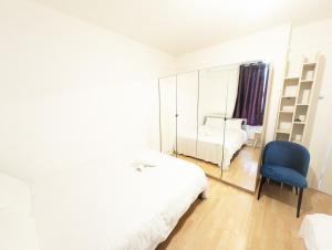 a white bedroom with a blue chair and a mirror at Tobacco Docks & St Katherine's Rooms in London