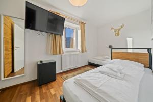 een slaapkamer met een bed en een flatscreen-tv bij Residence Alpin Kaprun - Top 6 by Four Seasons Apartments in Kaprun