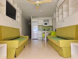 a living room with yellow and green couches and a kitchen at Tenerife Royal Gardens - Las Vistas TRG - Viviendas Vacacionales in Playa de las Americas