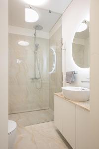 a white bathroom with a shower and a sink at Cathedral apartment, perfect for couples in Vilnius