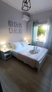 a bedroom with a white bed with a window at Katerina Holiday House in Anavyssos