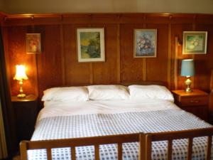 uma cama num quarto com duas lâmpadas e quadros na parede em Federation House em Oamaru