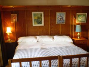 a bed in a bedroom with two lamps and pictures on the wall at Federation House in Oamaru