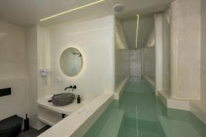 een badkamer met een bad, een wastafel en een spiegel bij Leon Luxury Suites in Imerovígli