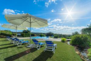 a group of chairs and an umbrella and a pool at Casas de Campo em Estoi by Garvetur in Estói