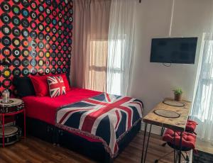 a bedroom with a bed with a red blanket and a tv at J&W Apartments with free parking in Liverpool