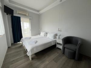 a white bedroom with a bed and a chair at Apartments Katoji in Chrani