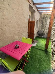 une table rose et des chaises vertes sur une terrasse dans l'établissement Appartement À Valence, à Valence