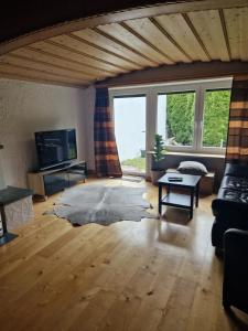 een woonkamer met een bank en een tv bij Ferienwonung in Pullenreuth