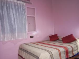タリオウイネにあるauberge souktanaのベッドルーム1室(赤い枕のベッド1台、窓付)