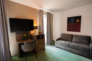 Hotel Barnimer Hof في فاندليتس: غرفة معيشة مع أريكة وتلفزيون بشاشة مسطحة