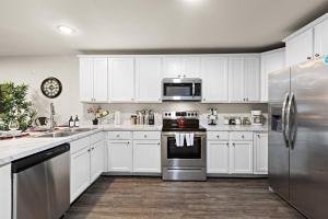 a kitchen with white cabinets and stainless steel appliances at Family & Traveler Haven - NYC & NWK w/free parking in Newark +18 photos