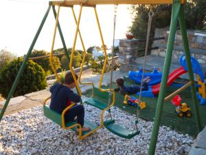 two boys playing on a swing set in a yard at Efi's apartment in Apróvaton