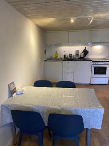 a kitchen with a table and blue chairs in a room at Idyliska boende mitt på Öland in Färjestaden