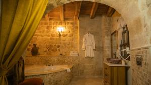 a bathroom with a tub and a robe hanging on the wall at Yeşil Konak Cave Hotel in Ürgüp +69 photos