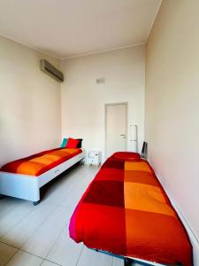 2 łóżka w białym pokoju z czerwonym i pomarańczowym w obiekcie Maison Climatisée avec Piscine w Tuluzie