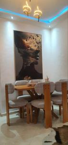 a dining room with a table and chairs and a painting at Appartement a louer martil in Martil