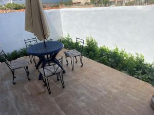 einen Tisch, Stühle und einen Regenschirm auf einer Terrasse in der Unterkunft Chalet villa familiale in Imouzzer du Kandar