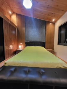 Schlafzimmer mit einem grünen Bett und Holzwänden in der Unterkunft Chalet villa familiale in Imouzzer du Kandar