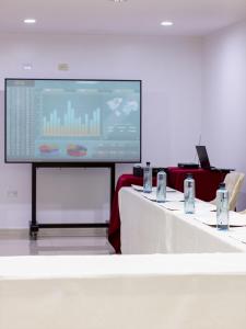 a meeting room with two tables and a projection screen at Hotel America Chiclayo in Chiclayo