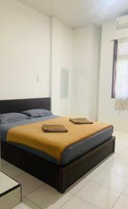 Una cama en una habitación blanca con dos toallas. en SEUNIA HOTEL, en Lamnyong