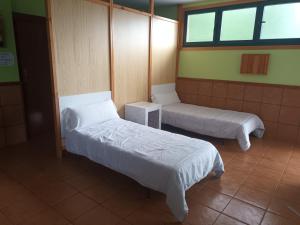 a room with two beds and two windows at A CONDA in Arzúa