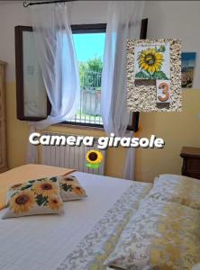sypialnia z łóżkiem z poduszkami słonecznikowymi i oknem w obiekcie Affittacamere Albafiorita w mieście Castiglione dʼOrcia