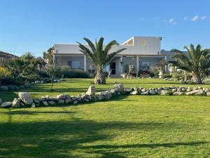 a house with a rock wall in front of a yard at Villa Aries - Rural Chic Experience in Gela