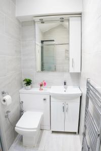 a white bathroom with a toilet and a sink at CRHeathrow in Stanwell +17 photos