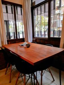 uma mesa de madeira com cadeiras num quarto com janelas em Plaza Mayor Andrea em Mendoza