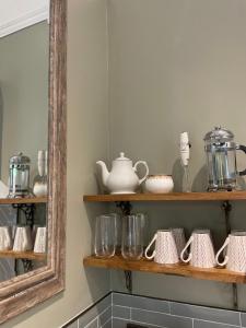 a shelf with dishes and cups and a mirror at Penarwyn House in Par