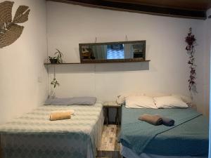 two beds in a room with a mirror on the wall at Conjunto Sol Roots in Pipa