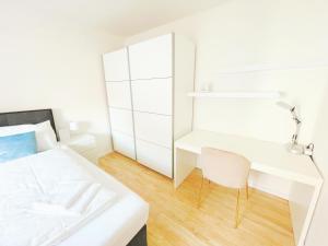 een witte slaapkamer met een wit bed en een bureau bij StayHere Central City Suite 11 - contactless Self-Check-IN in Graz