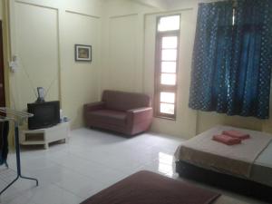 a room with a bed and a chair and a television at Saba Lodge Dungun in Dungun