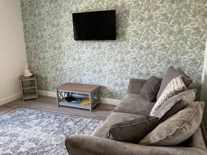 een woonkamer met een bank en een tv aan de muur bij River View in Hawick