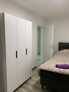 a bedroom with white cabinets and a bed with a purple pillow at Zlatna plaža in Bratunac
