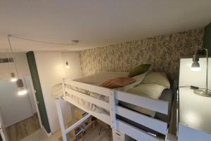 Ce lit superposé blanc se trouve dans un dortoir doté d'un mur. dans l'établissement Chambre chez Quentin y Kiara - Chez l'habitant, à Montpellier