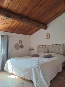 1 dormitorio con cama grande y techo de madera en Les Roses Trémières, en Bargème
