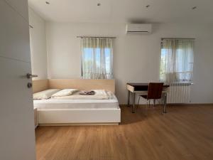 ein weißes Schlafzimmer mit einem Bett und einem Schreibtisch in der Unterkunft Villa Amela in Ilidža