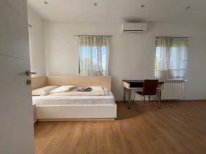 a white bedroom with a bed and a desk at Villa Amela in Ilidža