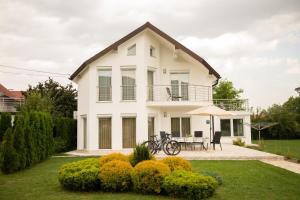 a white house with a table and an umbrella at Villa Amela in Ilidza